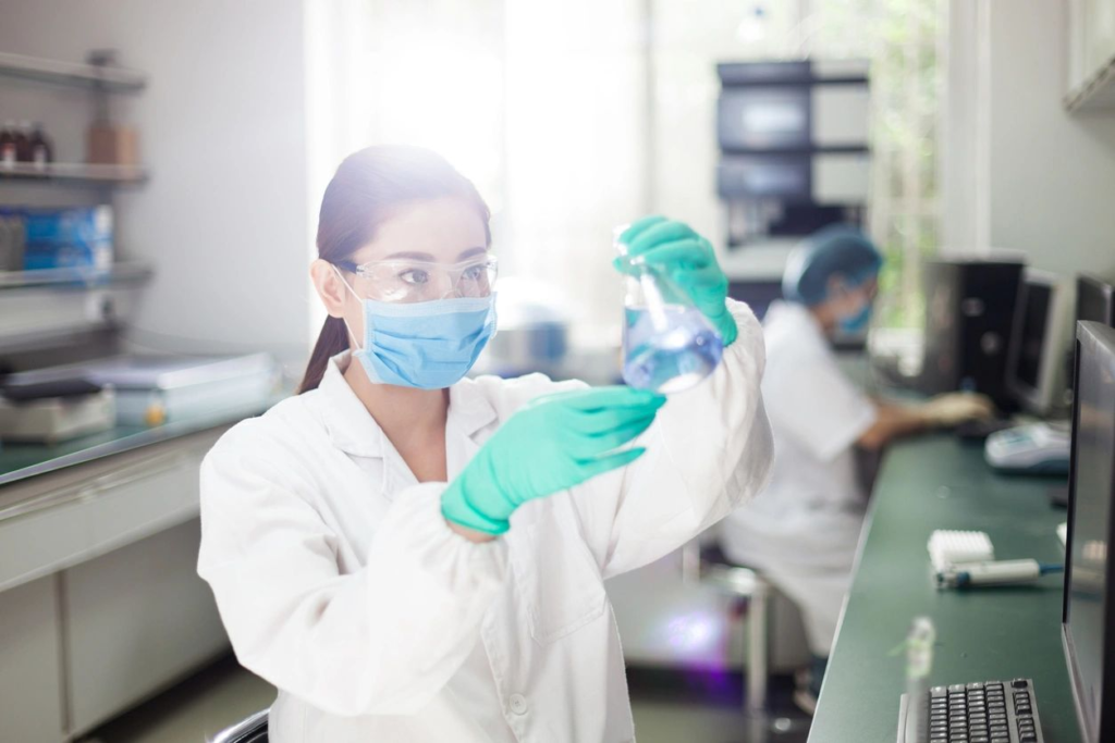 About Us, Capabilities: female scientist examining the contents in an Erlenmeyer flask